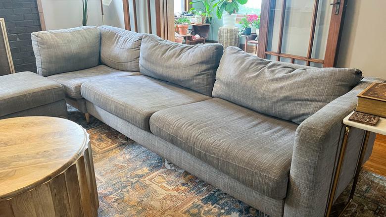 saggy gray sofa in living room with saggy, worn cushions