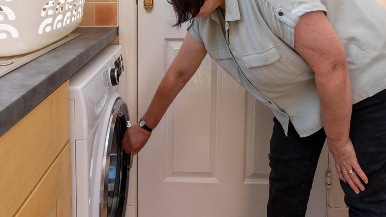 woman bending over washing machine