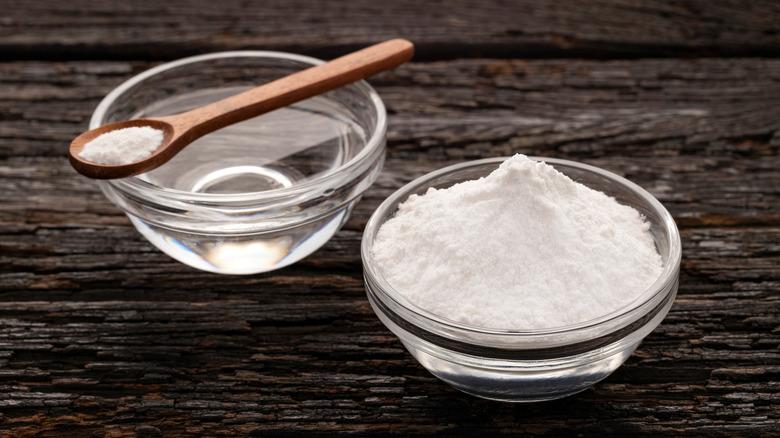 baking soda in a bowl with a wooden spoon holding baking soda over another bowl with water