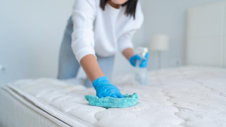 women spraying and wiping down mattress